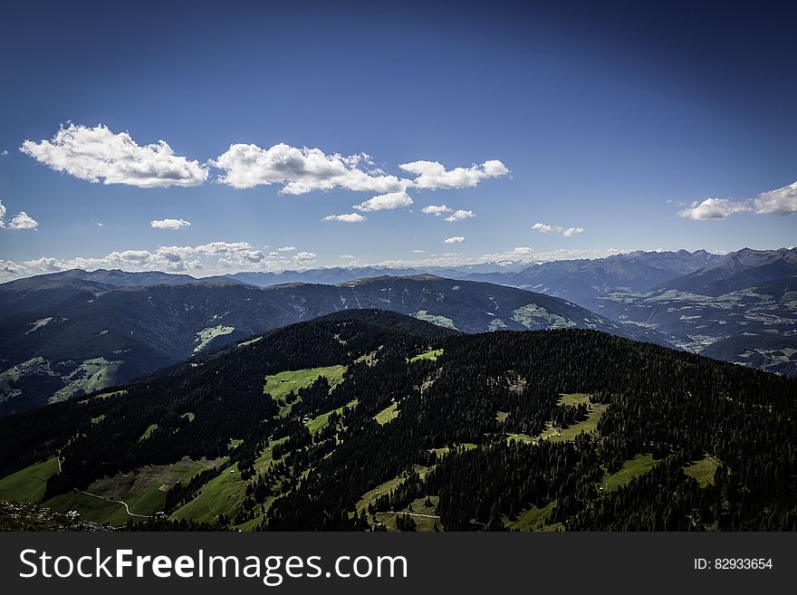 Aerial view over rolling green hill landscape with blue skies on sunny day. Aerial view over rolling green hill landscape with blue skies on sunny day.