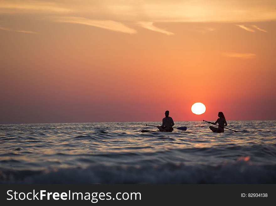 Man And Woman Boat Rowing In Sea During Golden Hour