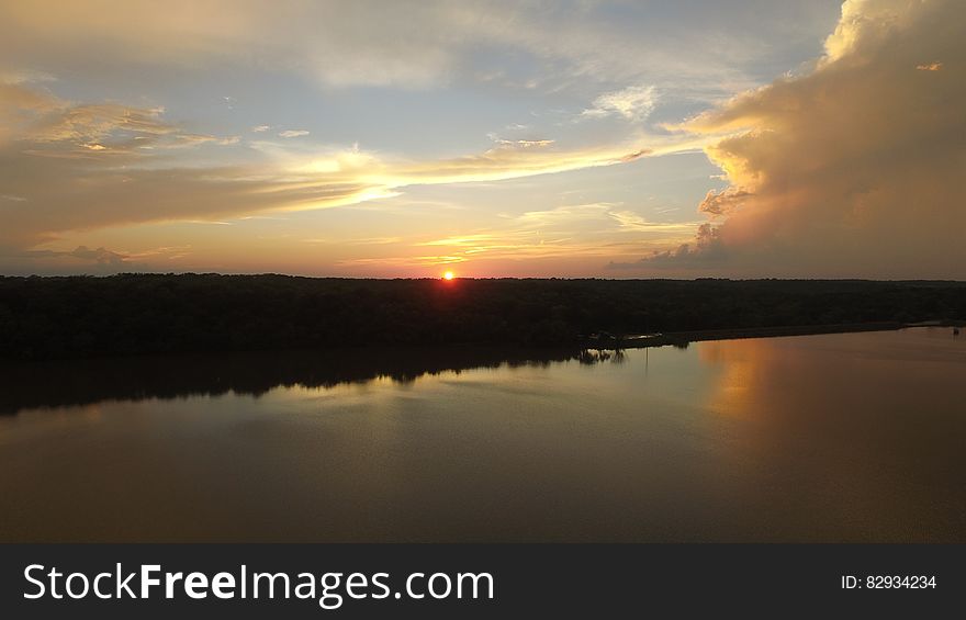 Sun setting behind the horizon by a lake. Sun setting behind the horizon by a lake.