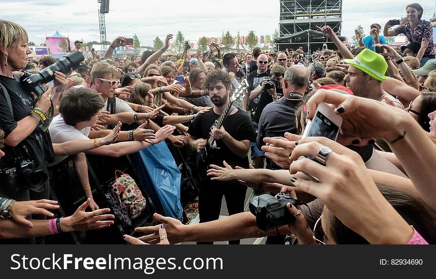 Man in Black Crew Neck T Shirt and Pants Playing Guitar Surrounded by Crowd