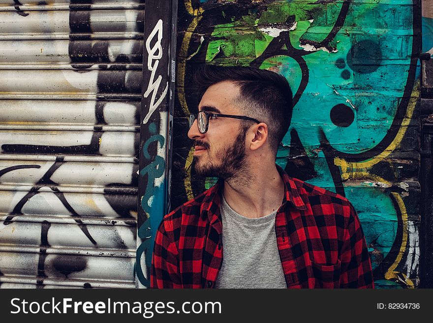 Man Wearing Black Framed Eyeglasses Standing Beside Blue and Black Wall