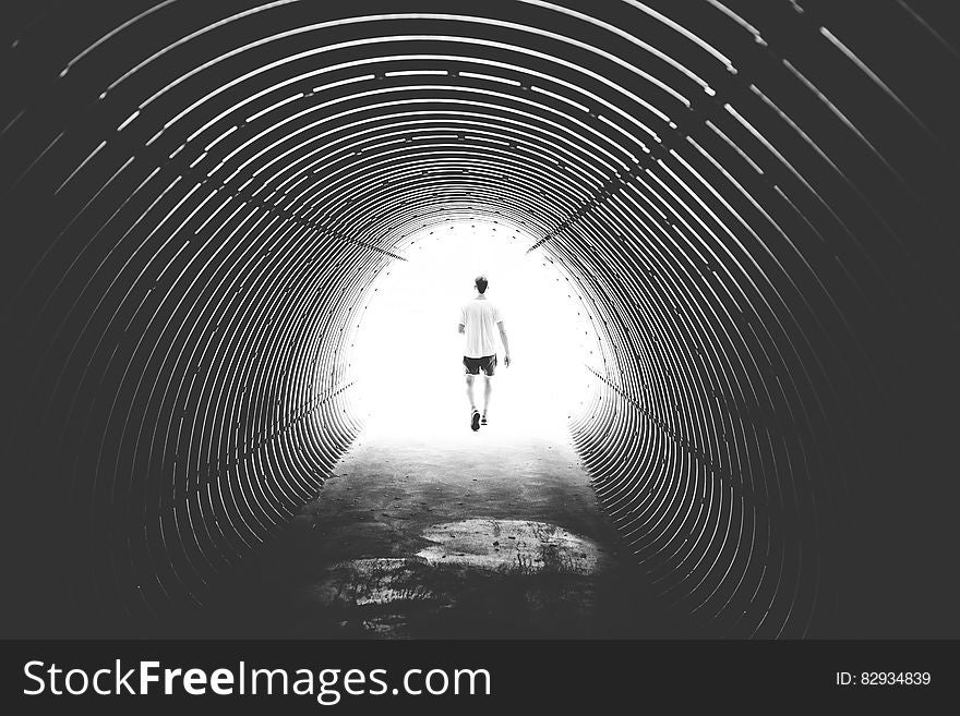 Grayscale Photo of Man Walking in Hole