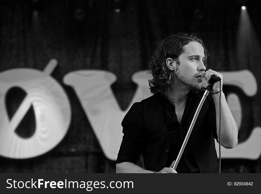 Grayscale Photography of Man Wearing Dress Shirt While Holding Microphone