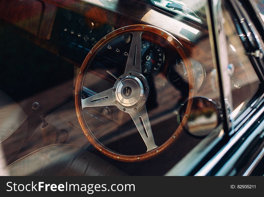 Wooden steering wheel inside automobile through window.