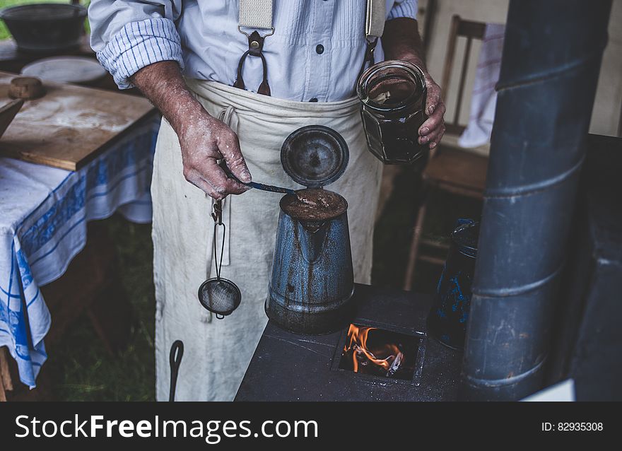 Man Holding Jar While Scooping on Kettle