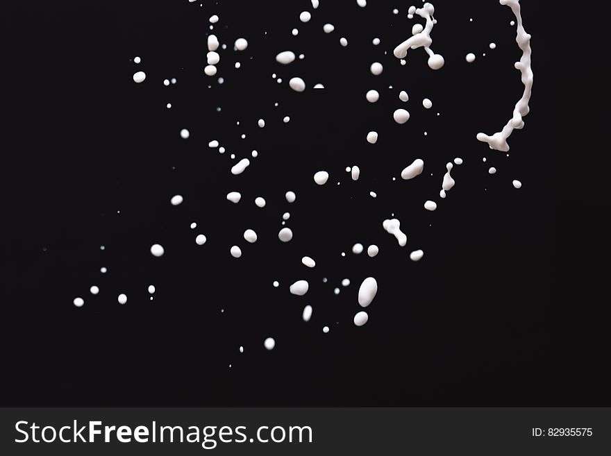 White milk droplets floating against black background. White milk droplets floating against black background.