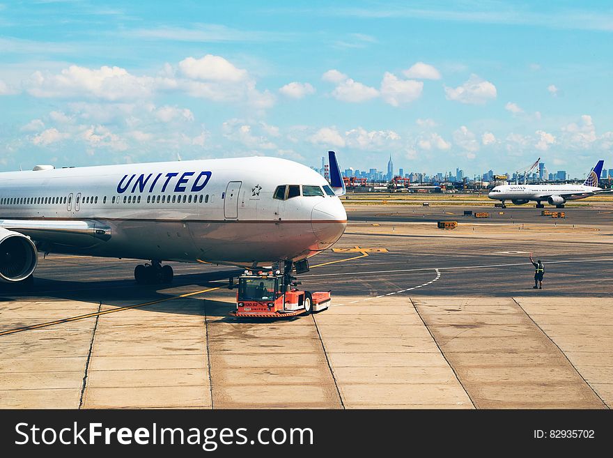 United Airlines plane being pushed from gate onto tarmac in airport on sunny day. United Airlines plane being pushed from gate onto tarmac in airport on sunny day.