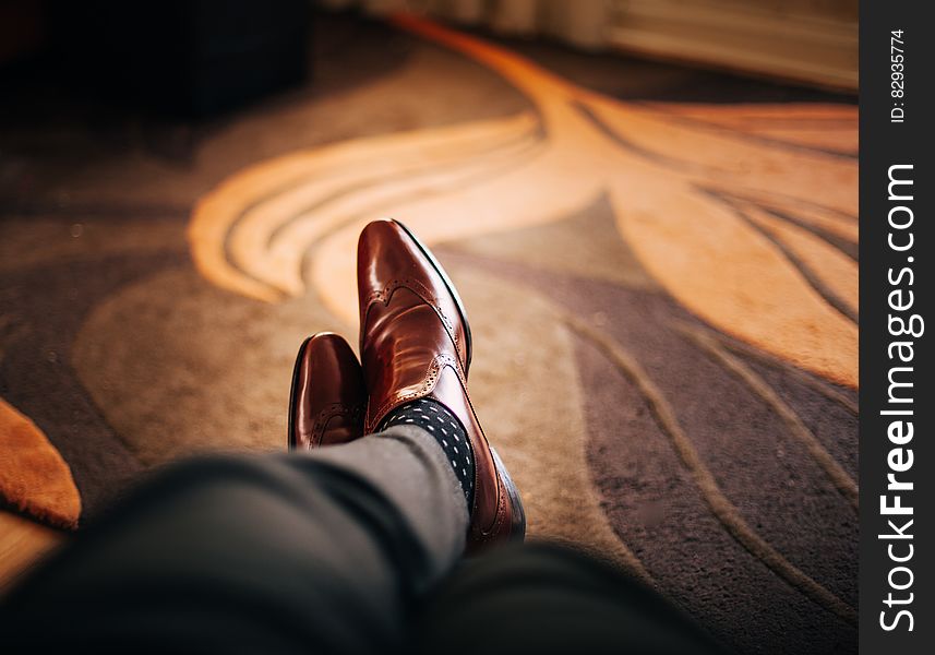 Close up of brown leather shoes on feet of mat resting on rug. Close up of brown leather shoes on feet of mat resting on rug.