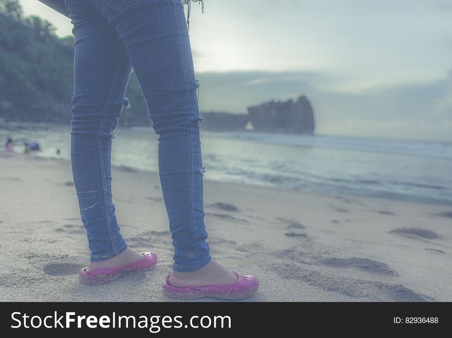 Person in Blue Jeans and Pink Flats in Front of Seashore
