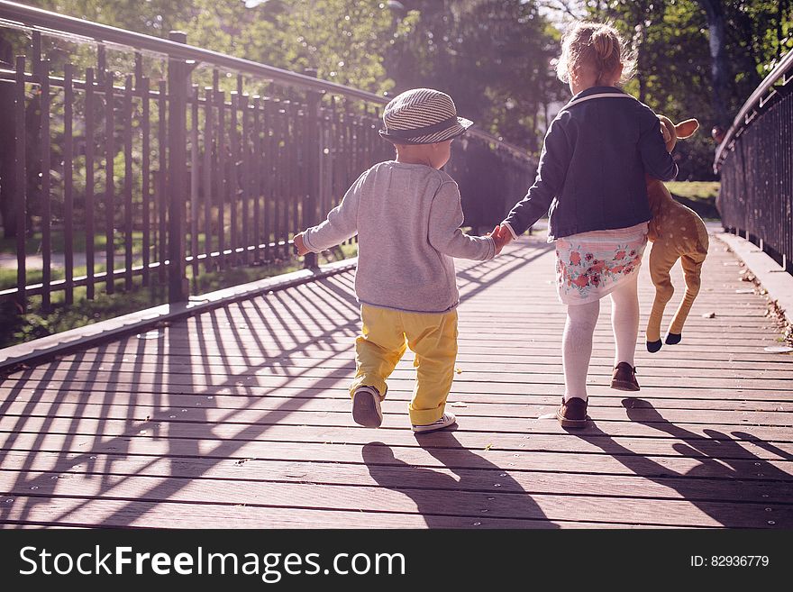 Boy and Girl Walking on Bridge during Daytime
