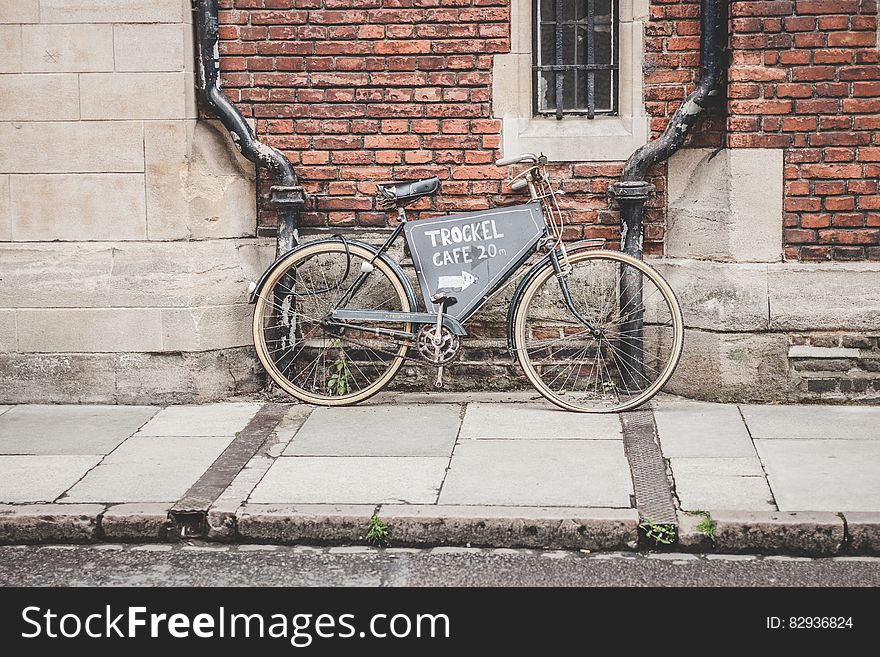 A bicycle with an advertisement leaning on a brick wall on a street. A bicycle with an advertisement leaning on a brick wall on a street.