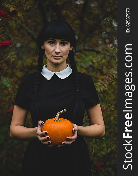 Woman in Black and White Collared Dress Holding Pumpkin during Daytime