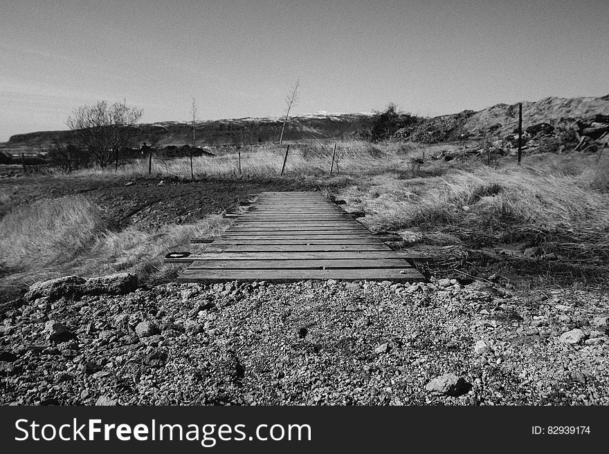 A black and white view of a small bridge crossing a stream. A black and white view of a small bridge crossing a stream.