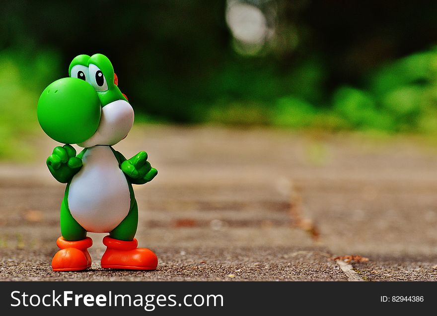 Green And White Dinosaur Toy On Brown Ground In Tilt Shift Photography