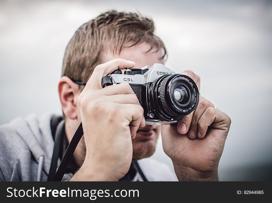 Man Holding Black Silver Bridge Camera Taking Photo during Daytime