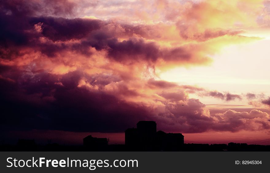 Colorful sunset and dark storm clouds over silhouetted building. Colorful sunset and dark storm clouds over silhouetted building.