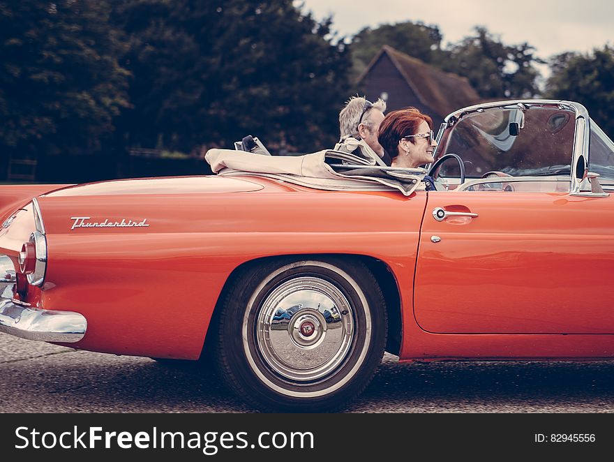 Couple Riding Red Ford Thunderbird during Daytime