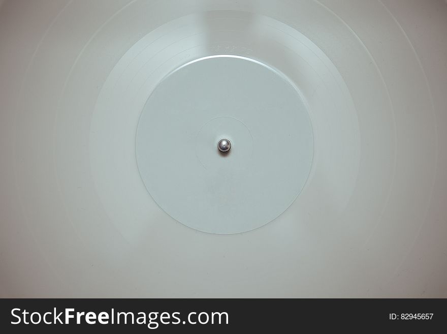 A white vinyl record on a record player, top view.