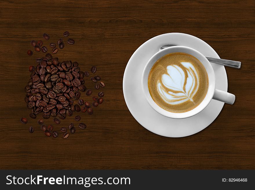 Brown And White Espresso In White Coffee Mug Beside Coffee Beans