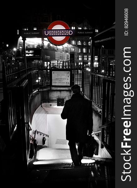 Rear view of businessman walking down steps to London underground metro station at night. Rear view of businessman walking down steps to London underground metro station at night.