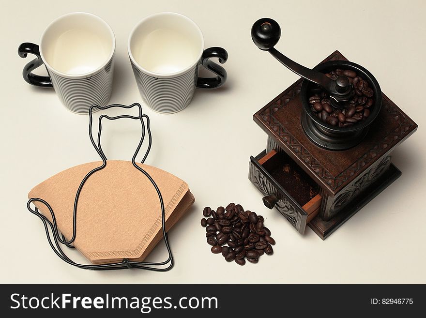 Still life of cat shaped coffee filter holder with cat tails on mugs and antique coffee mill. Still life of cat shaped coffee filter holder with cat tails on mugs and antique coffee mill.