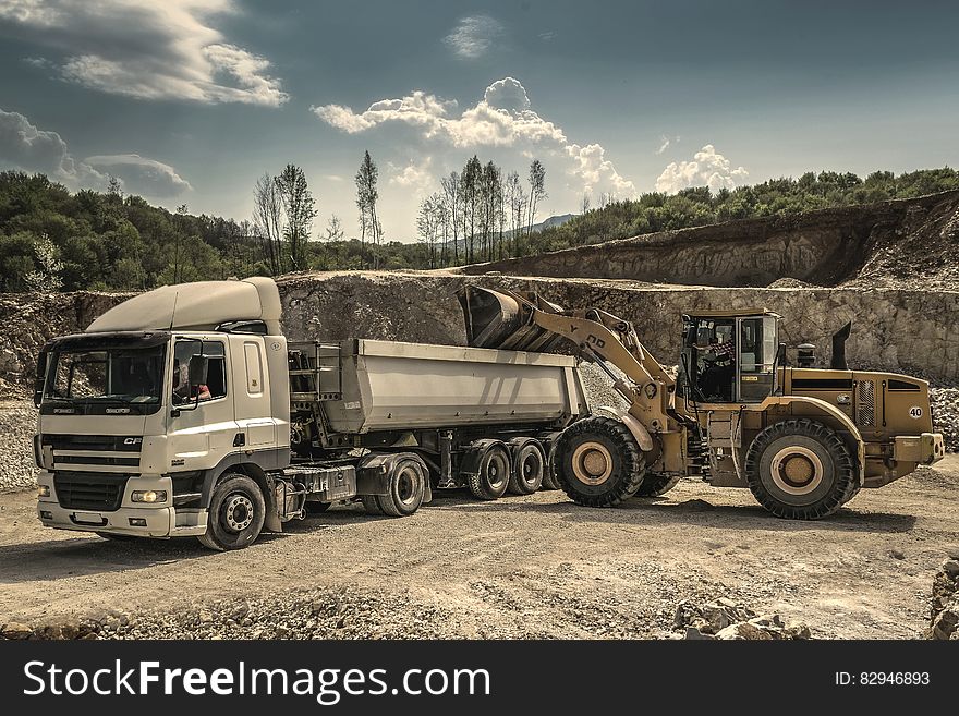 Front Load Loader Beside White Dump Truck