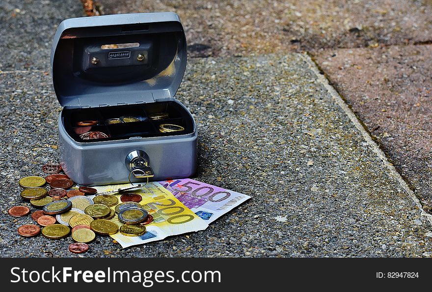 Open lock box on sidewalk outdoors with Euro bills and coins. Open lock box on sidewalk outdoors with Euro bills and coins.