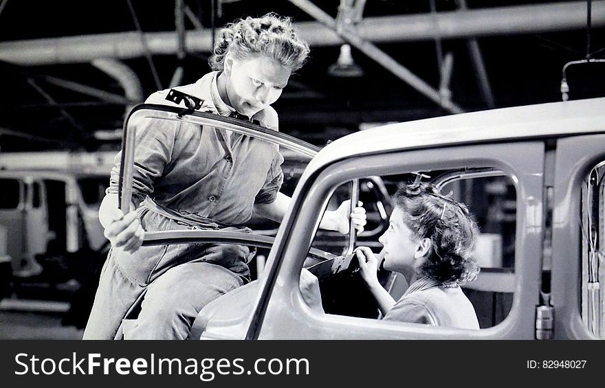 Man Carrying Car Windshield With Woman Inside a Car