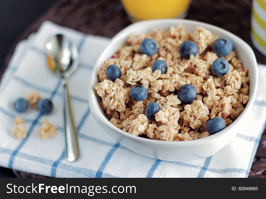 Bowl of breakfast granola with fresh blueberries with spoon on napkin. Bowl of breakfast granola with fresh blueberries with spoon on napkin.
