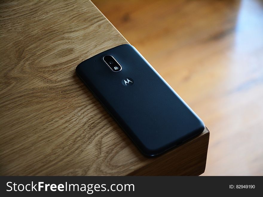 Black Motorola Smartphone on Top of Brown Wooden Table