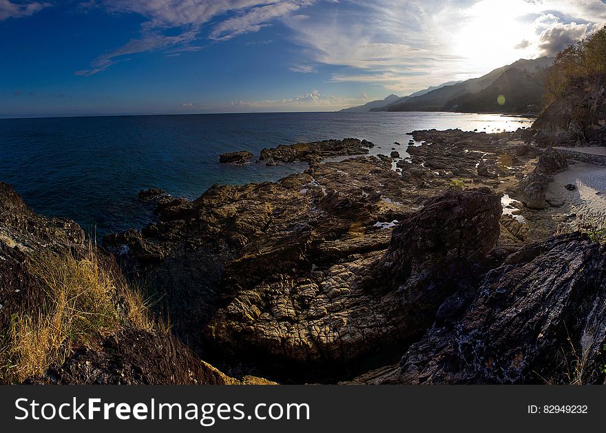 Sunlight over remote empty rocky coastline with blue skies. Sunlight over remote empty rocky coastline with blue skies.