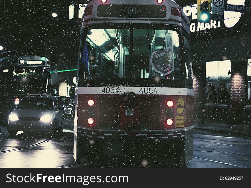 Train On Road Beside Cars During Nighttime