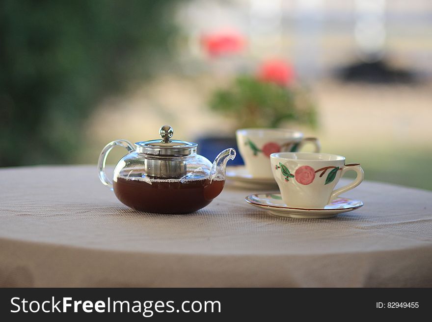 Pot of tea and two tea cups on garden table. Pot of tea and two tea cups on garden table.