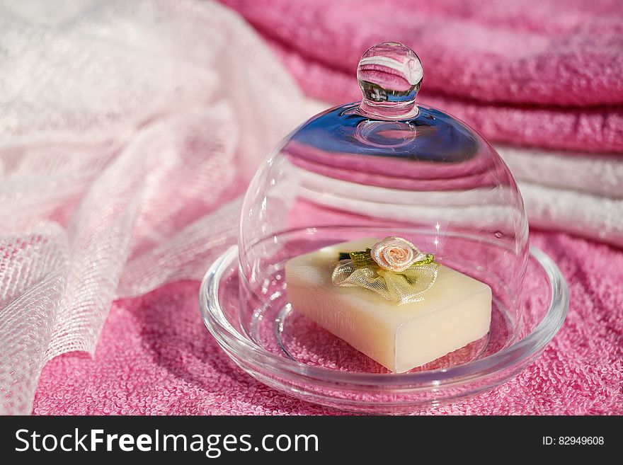 Purple and white towels and piece of soap with floral decoration in closed glass soap dish ready for relaxing bath. Purple and white towels and piece of soap with floral decoration in closed glass soap dish ready for relaxing bath.