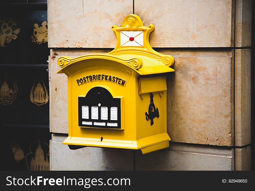 Yellow Postbriefkasten Floating Mailbox on Brown Concrete Wall