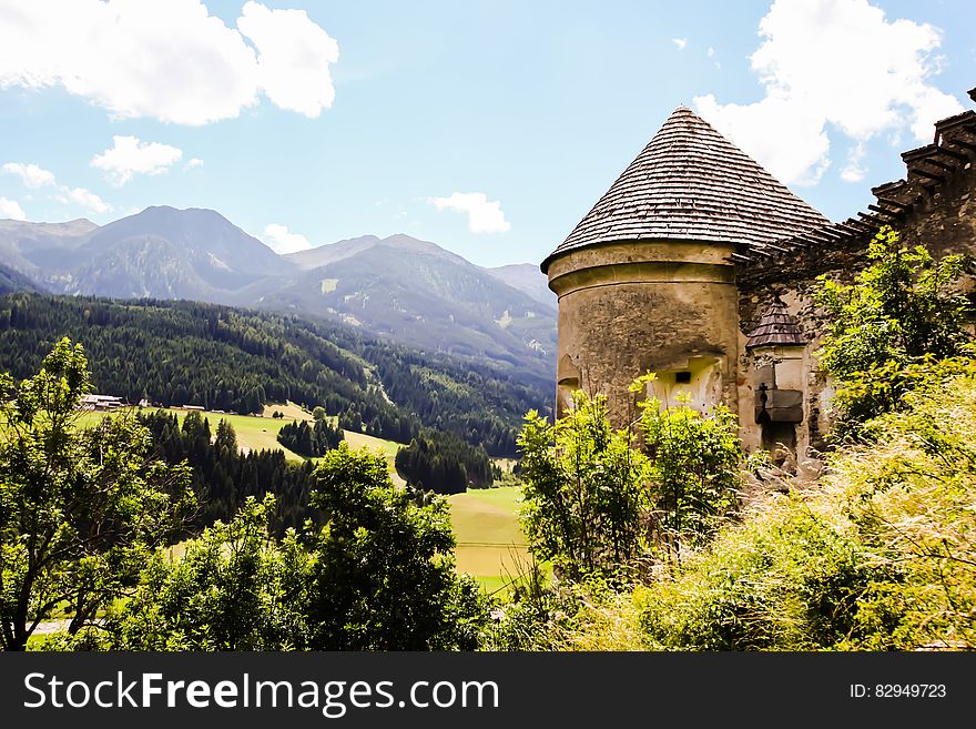 Brown Concrete House Beside Green Tree And Far Mountain On Daytime