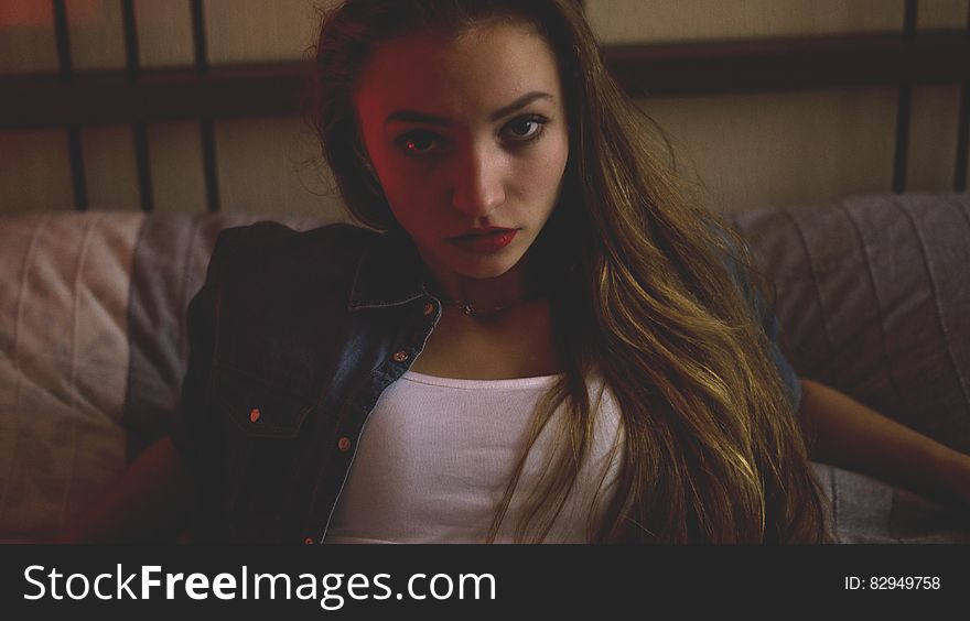 Woman In Blue Denim And White Shirt Sitting Inside Brown Painted Room