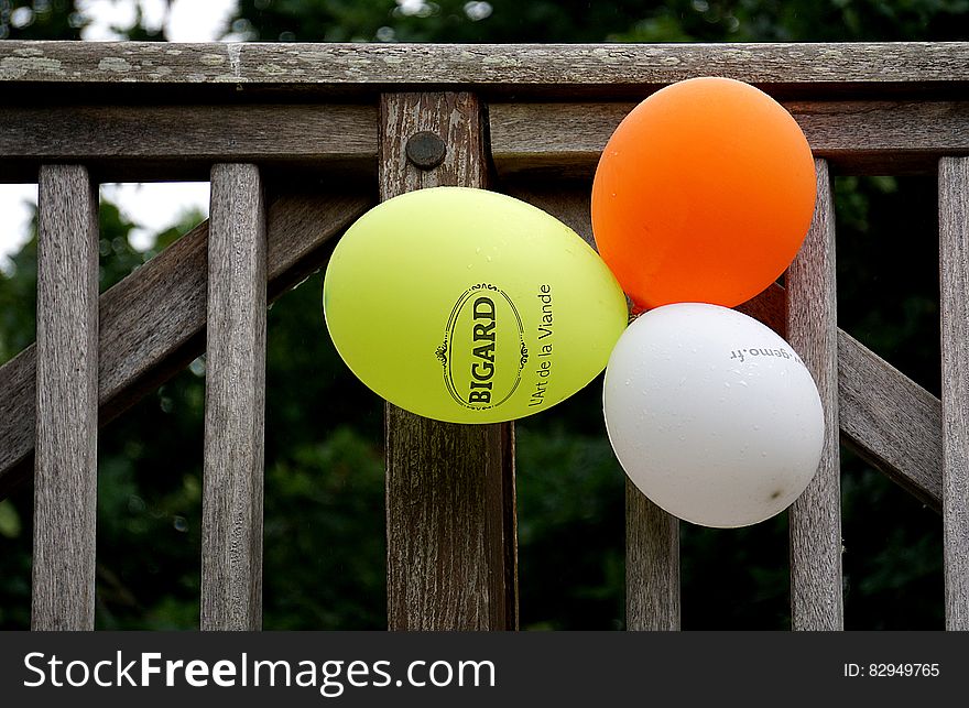 Yellow Orange And White Balloon Beside Gray Wooden Fence