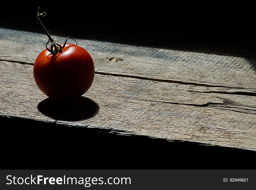 Red ripe whole tomato on worn wooden plank in sunlight. Red ripe whole tomato on worn wooden plank in sunlight.