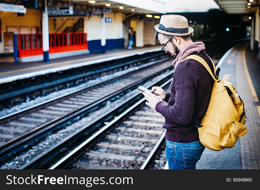 Man In Brown Hoodie Standing In Front Of Train Railway