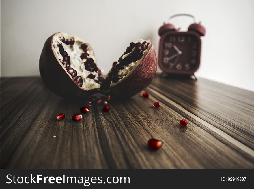 Red and White Round Fruit on Brown Wooden Table With Red Alarm Clock