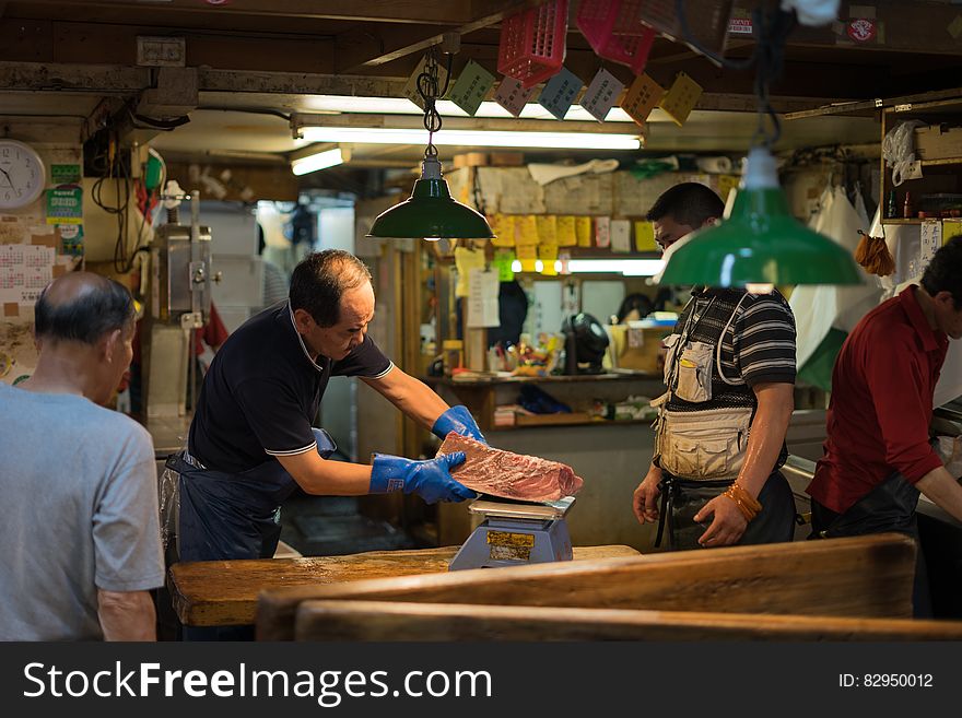 Workers cutting meat inside Asian butcher shop.