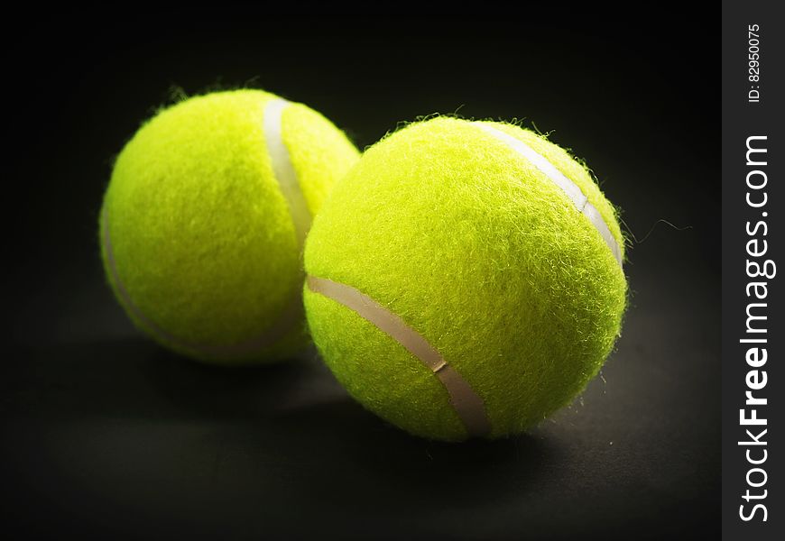Close up of yellow tennis balls on black.