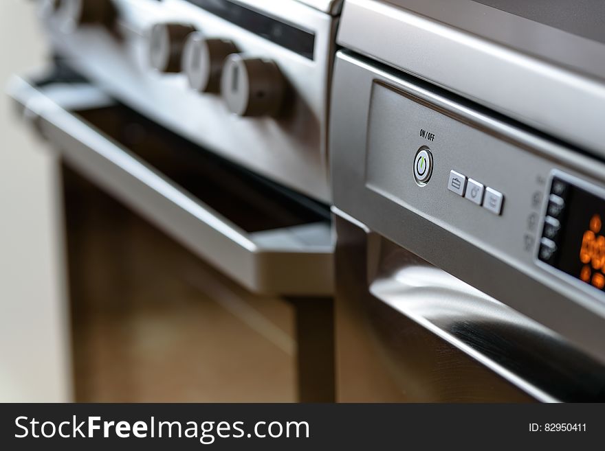 Closeup of modern kitchen cooker and dishwasher appliance with electronic display.