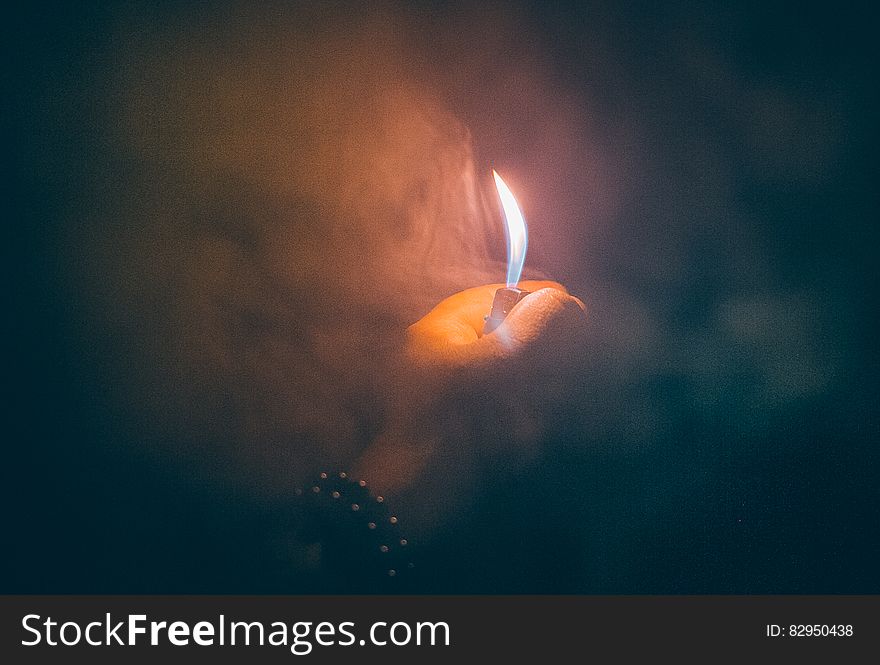 Close up of hand holding small lighter in smoke. Close up of hand holding small lighter in smoke.