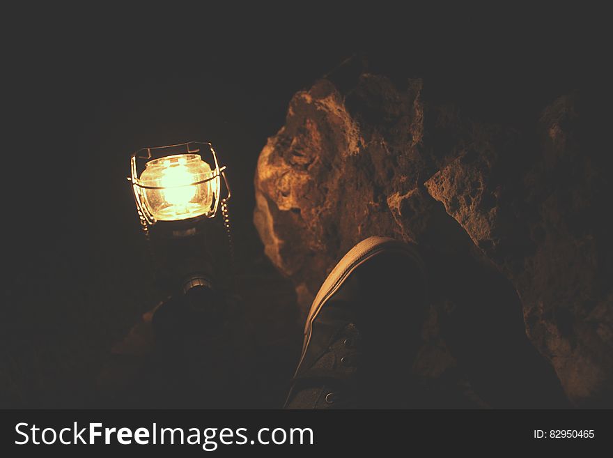 Person Wearing Sneakers Sitting Near Kerosene Lamp