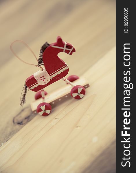 A red toy horse as a Christmas ornament on a wooden surface. A red toy horse as a Christmas ornament on a wooden surface.