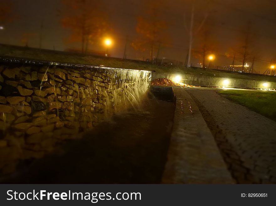 Close up of stone wall with lights along roadway at night. Close up of stone wall with lights along roadway at night.