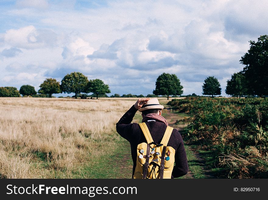 Man in Black Long Sleeve Shirt Walking Between Grass during Daytime
