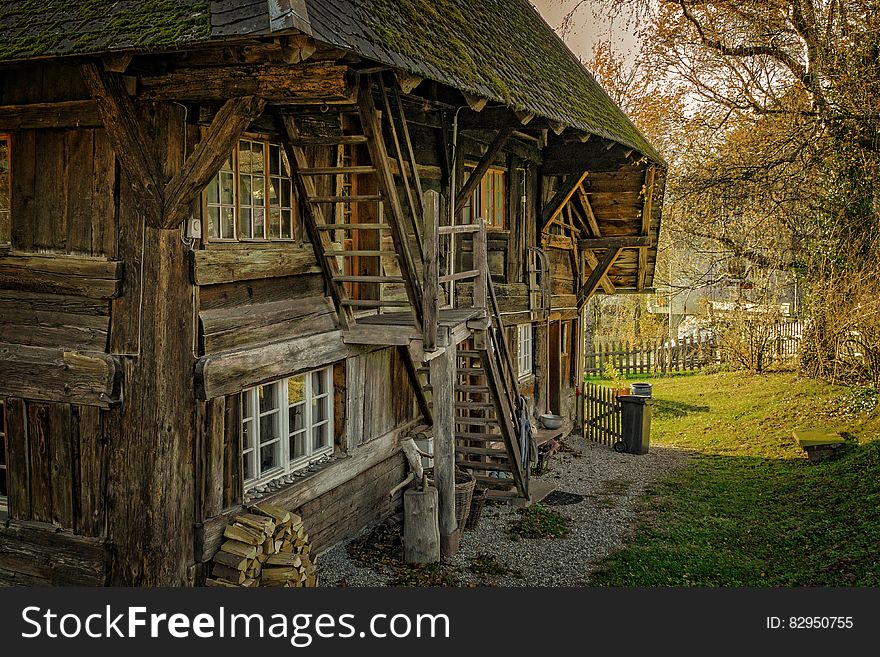 Exterior of rustic wooden log farm house in green field on sunny day. Exterior of rustic wooden log farm house in green field on sunny day.